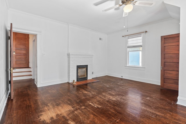 unfurnished living room featuring a brick fireplace, ornamental molding, ceiling fan, and dark hardwood / wood-style flooring