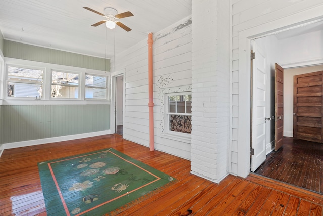 interior space featuring wood walls, hardwood / wood-style flooring, ceiling fan, and a wealth of natural light