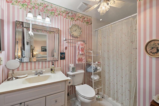 bathroom featuring ceiling fan, toilet, tile floors, and vanity with extensive cabinet space