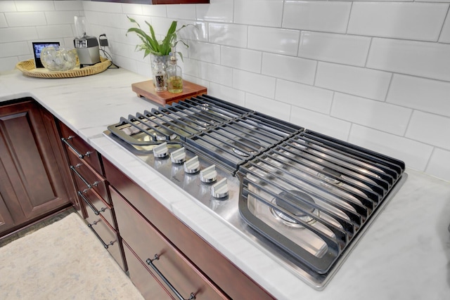 details with stainless steel gas stovetop and tasteful backsplash