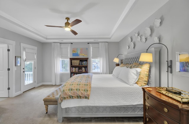 carpeted bedroom with ceiling fan, a raised ceiling, and access to exterior