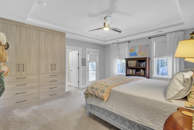 bedroom featuring light carpet, ceiling fan, and a tray ceiling