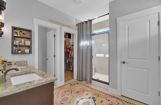 bathroom featuring tile patterned flooring, walk in shower, and vanity