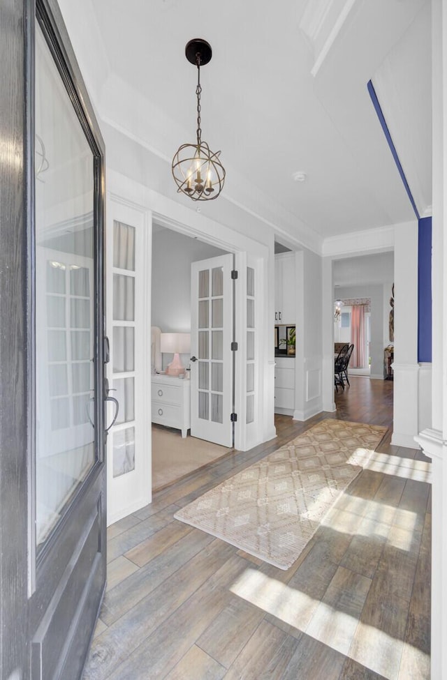 entrance foyer with hardwood / wood-style flooring, an inviting chandelier, and french doors