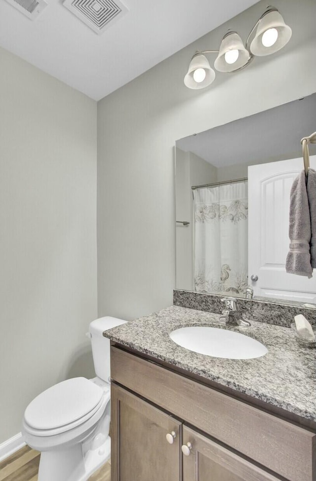 bathroom featuring wood-type flooring, toilet, and vanity