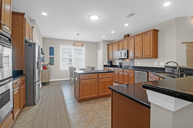 kitchen with appliances with stainless steel finishes, a sink, brown cabinets, light tile patterned floors, and recessed lighting