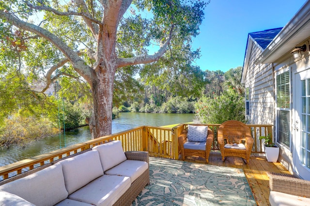 wooden terrace featuring an outdoor hangout area, a water view, and view of wooded area