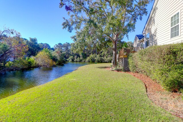 view of grassy yard with a deck with water view