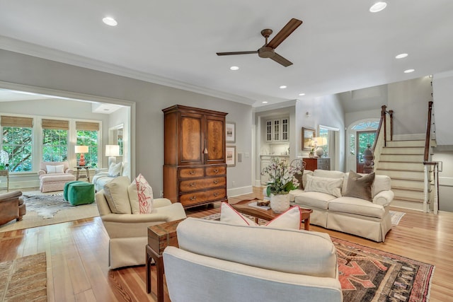 living room featuring light hardwood / wood-style floors, ornamental molding, and ceiling fan