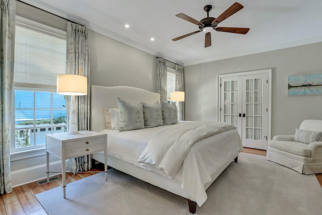 bedroom featuring ornamental molding, light hardwood / wood-style flooring, ceiling fan, and french doors