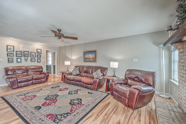 living room featuring ceiling fan, a textured ceiling, baseboards, and wood finished floors