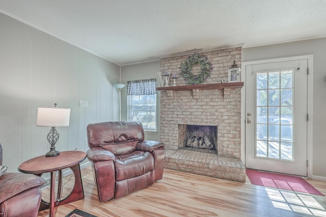 living room featuring ornamental molding, a brick fireplace, a textured ceiling, and wood finished floors