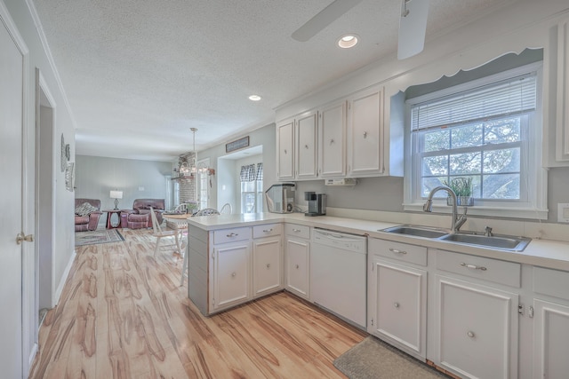 kitchen with a peninsula, a sink, white cabinets, dishwasher, and light wood finished floors