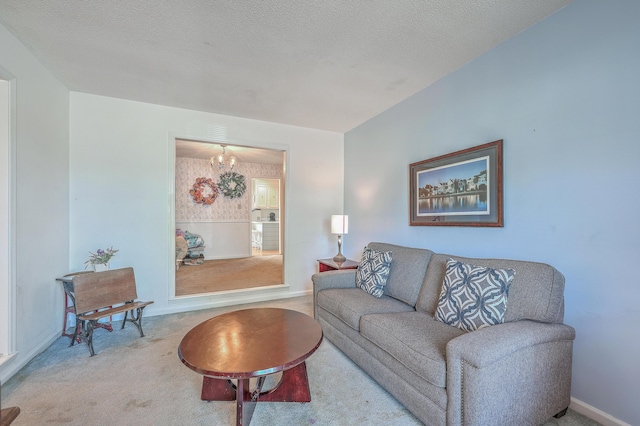 carpeted living area with a textured ceiling, baseboards, an inviting chandelier, and wallpapered walls