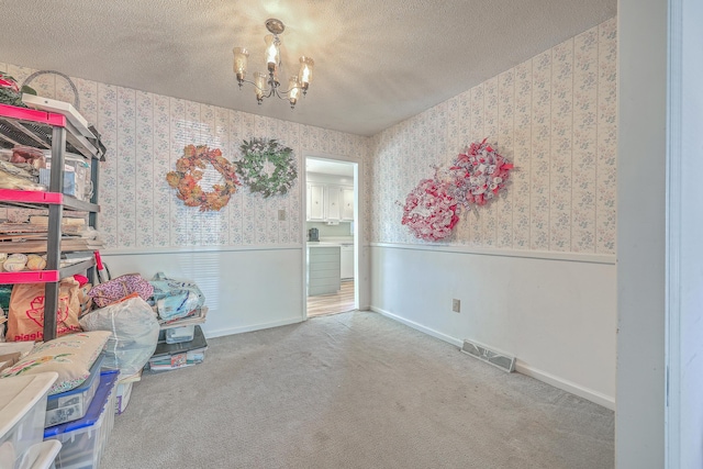 interior space with visible vents, wainscoting, a textured ceiling, and wallpapered walls