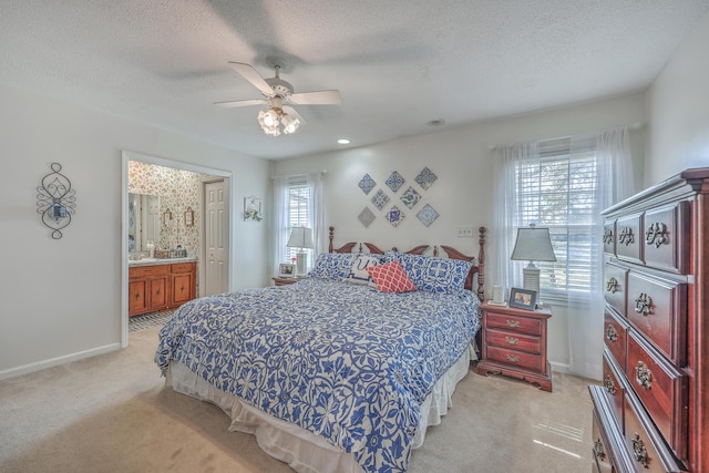 bedroom with light carpet, baseboards, ceiling fan, ensuite bathroom, and a textured ceiling