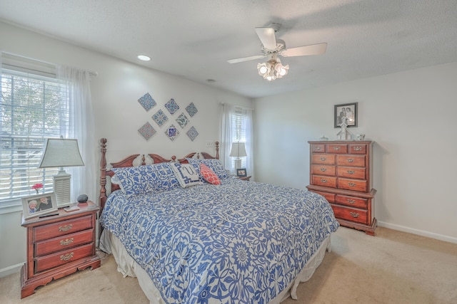 bedroom with light carpet, a textured ceiling, a ceiling fan, and baseboards