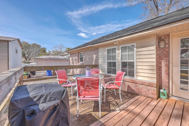 wooden terrace featuring area for grilling and outdoor dining space