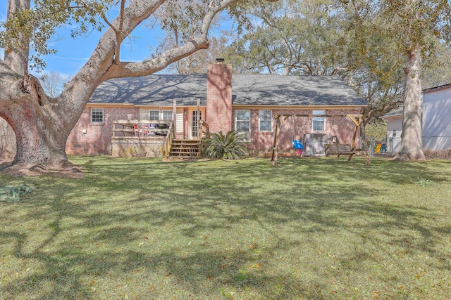 rear view of property with brick siding, a yard, and a chimney