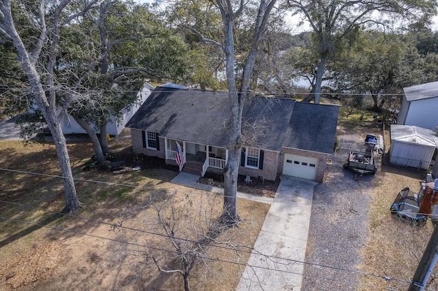 view of front of home with a garage, a shingled roof, concrete driveway, a porch, and brick siding