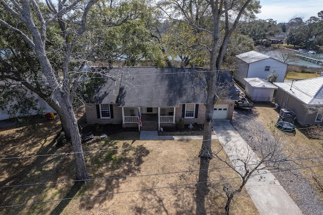 view of front of home featuring covered porch, a garage, brick siding, concrete driveway, and roof with shingles