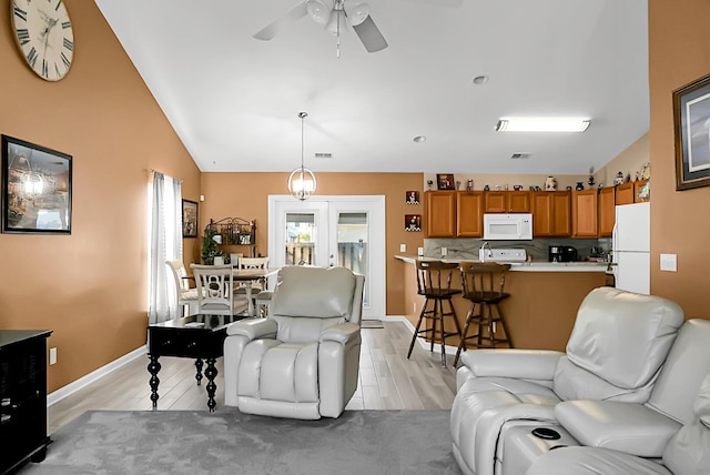 living room featuring lofted ceiling, ceiling fan, light hardwood / wood-style flooring, and french doors