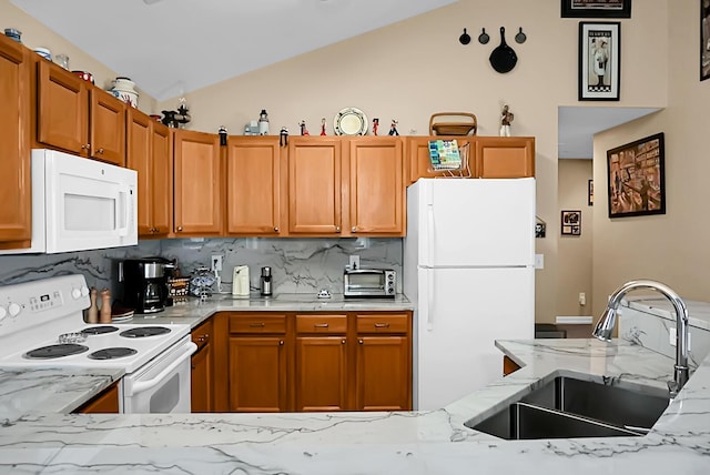 kitchen featuring white appliances, backsplash, sink, vaulted ceiling, and light stone counters