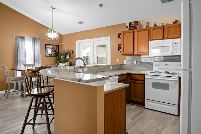 kitchen featuring lofted ceiling, white appliances, hanging light fixtures, a notable chandelier, and a breakfast bar area