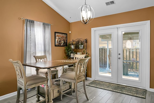 dining room featuring french doors, lofted ceiling, plenty of natural light, and a notable chandelier