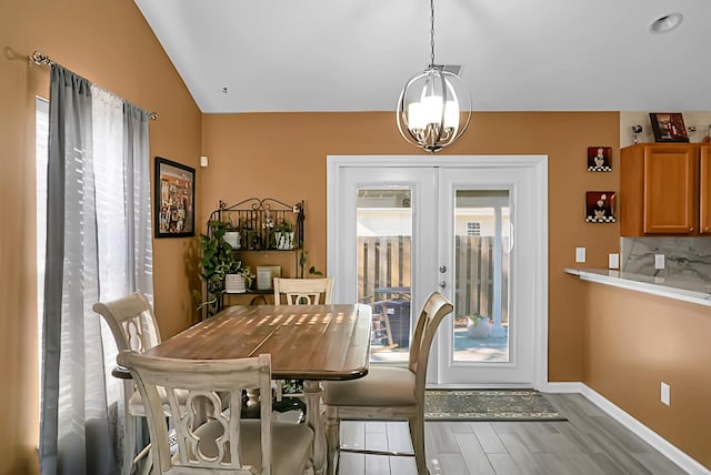 dining area with french doors, light hardwood / wood-style floors, an inviting chandelier, and lofted ceiling