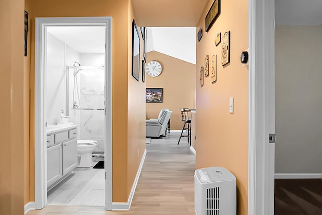 corridor featuring light hardwood / wood-style floors and vaulted ceiling