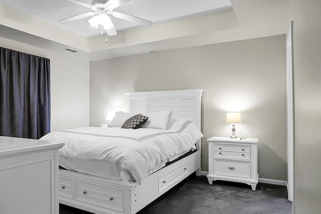 carpeted bedroom featuring ceiling fan and a tray ceiling