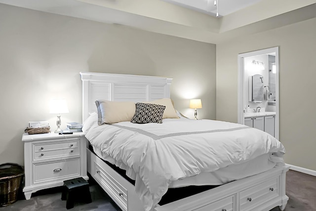 bedroom featuring ensuite bath and dark colored carpet