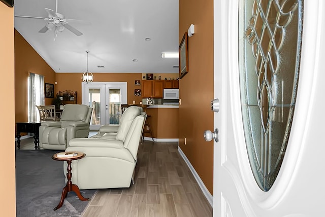 living room with french doors, ceiling fan, lofted ceiling, and wood-type flooring