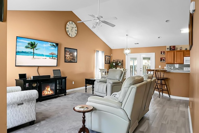 living room featuring ceiling fan, french doors, sink, light hardwood / wood-style floors, and lofted ceiling