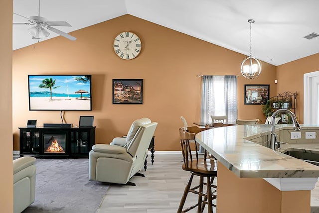 interior space with sink, ceiling fan with notable chandelier, light hardwood / wood-style floors, and lofted ceiling