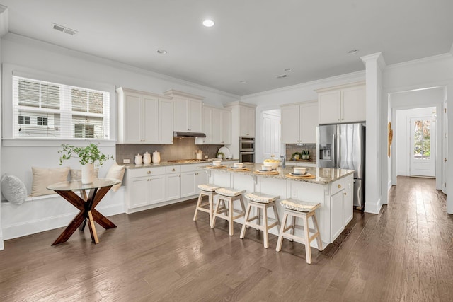 kitchen featuring a kitchen island, appliances with stainless steel finishes, breakfast area, and white cabinetry