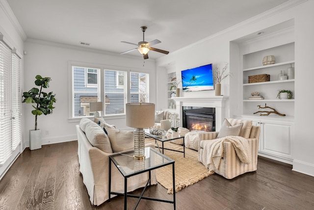 living room with ceiling fan, built in features, ornamental molding, and dark hardwood / wood-style flooring