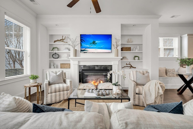 living room with wood-type flooring, ceiling fan, built in shelves, and crown molding