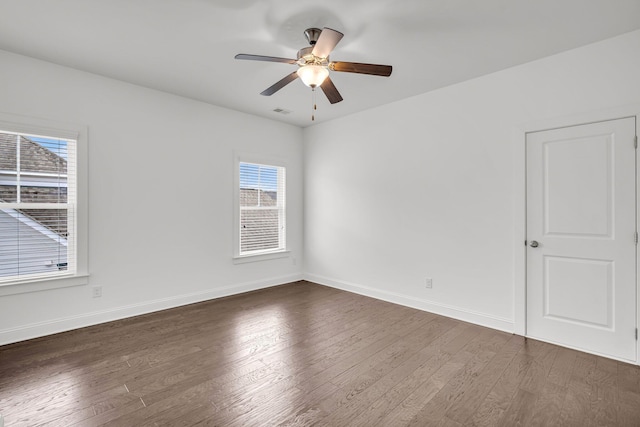 empty room featuring dark hardwood / wood-style flooring, ceiling fan, and a wealth of natural light