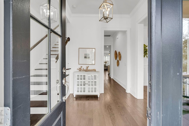 foyer with an inviting chandelier, ornamental molding, and dark wood-type flooring