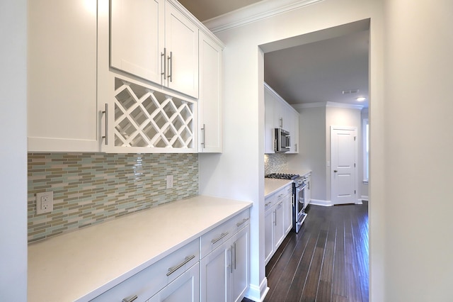 kitchen featuring ornamental molding, appliances with stainless steel finishes, white cabinetry, backsplash, and dark hardwood / wood-style flooring