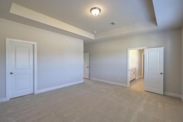 carpeted spare room with a raised ceiling