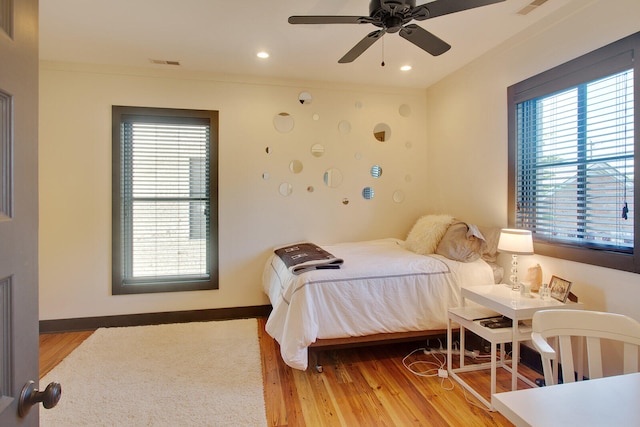 bedroom featuring multiple windows, ceiling fan, and light wood-type flooring