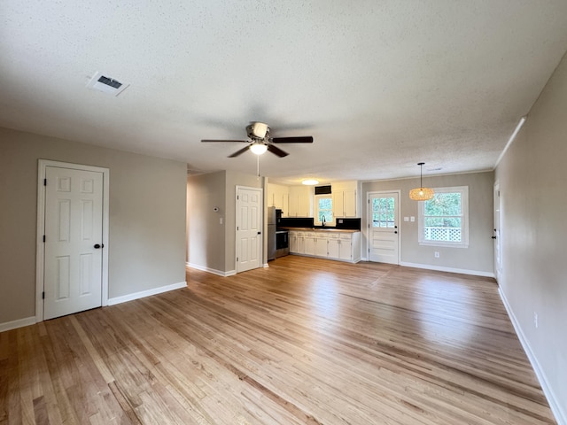 105 Dandridge Rd, Walterboro, SC 29488 - unfurnished living room featuring light wood finished floors, a ceiling fan, a textured ceiling, baseboards, and a sink