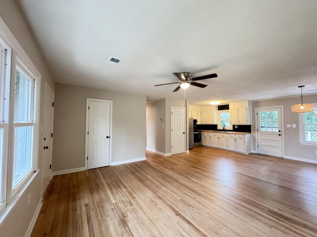 105 Dandridge Rd, Walterboro, SC 29488 - unfurnished living room featuring light wood finished floors, baseboards, a ceiling fan, a sink, and a textured ceiling
