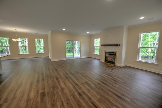 unfurnished living room with an inviting chandelier, dark wood-type flooring, ornamental molding, and a large fireplace