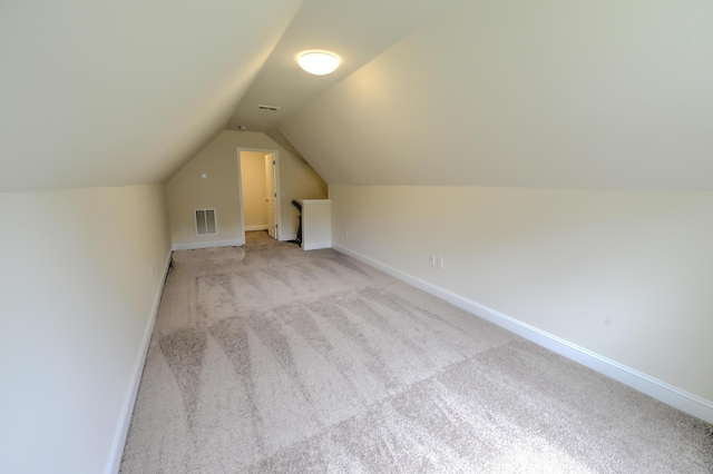 bonus room with lofted ceiling and light colored carpet