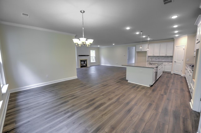 kitchen featuring pendant lighting, white cabinetry, sink, a kitchen island with sink, and dark wood-type flooring