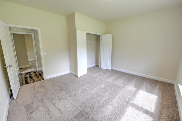 unfurnished bedroom with light colored carpet and a closet